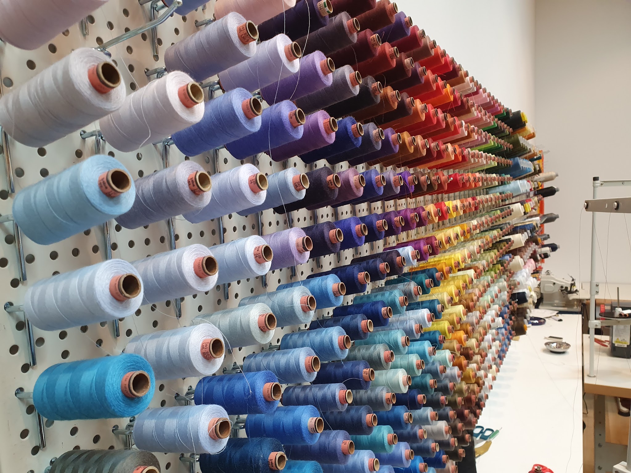 Honderden klossen garen in alle kleuren aan de wand van het atelier