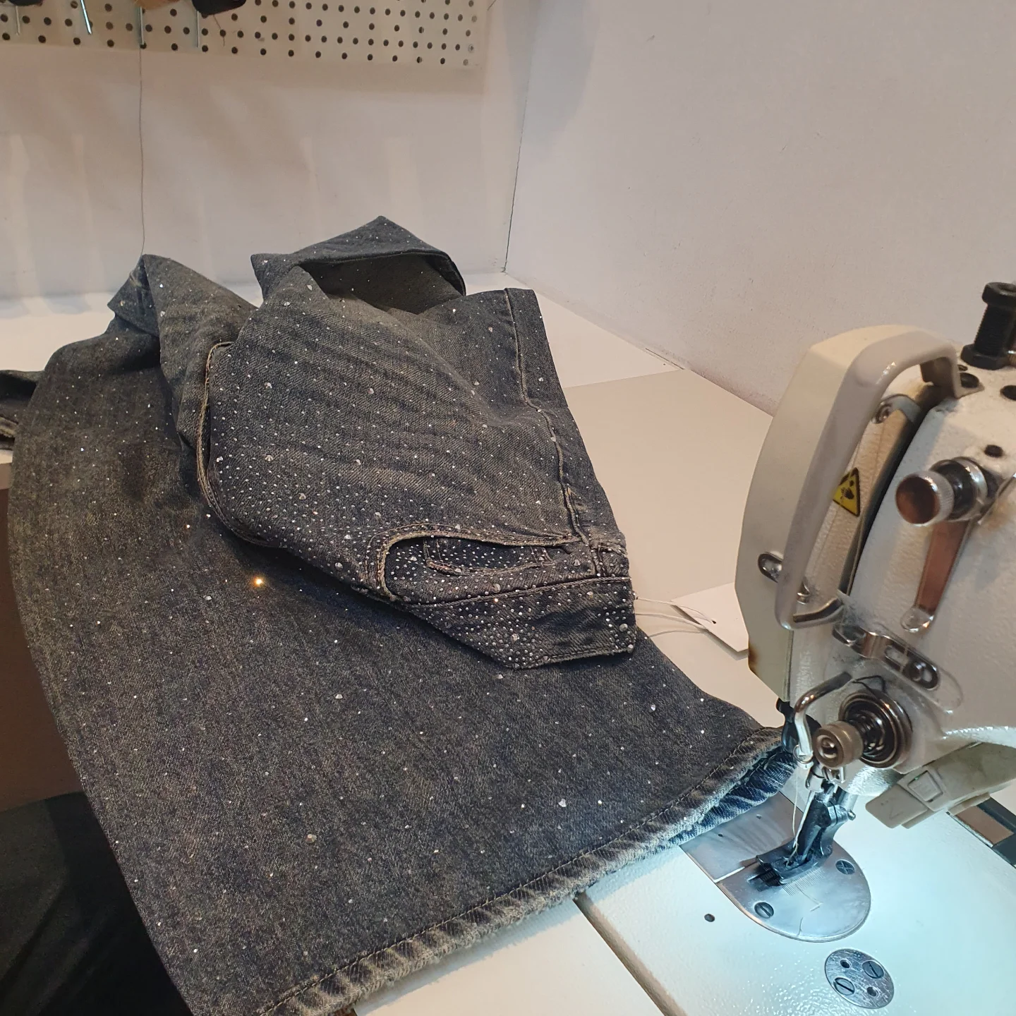 Een glitterjeans wordt op de zoommachine ingekort
